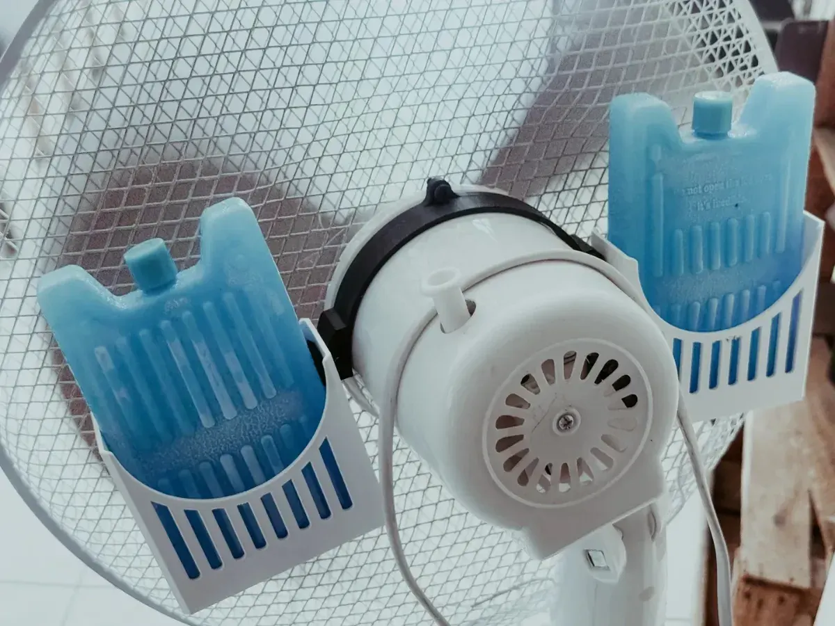 Deux supports blancs tenant des pains de glace bleus de chaque côté d’un ventilateur