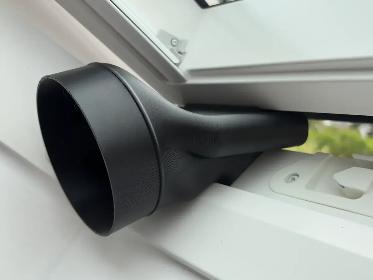 Adaptateur noir imprimé en 3D, fixé sur une fenêtre de toit et raccordé à une gaine de climatiseur